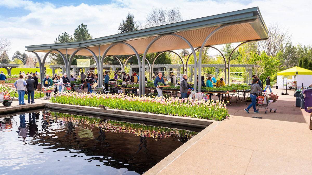 pool with flower bed on side and people browsing plants for sale in roofed area at Denver Botanic Garden in Denver, Colorado, USA